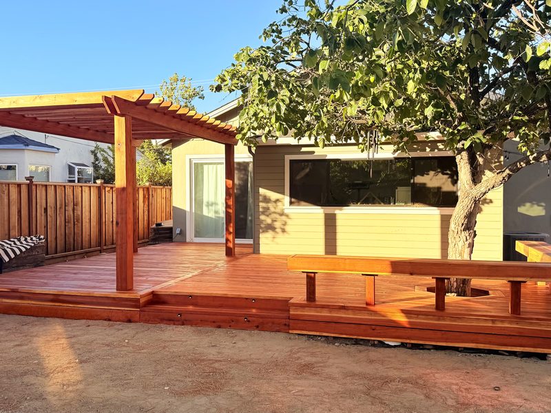 Redwood deck with a pergola and a bench around the tree, built by MS Construction and Services